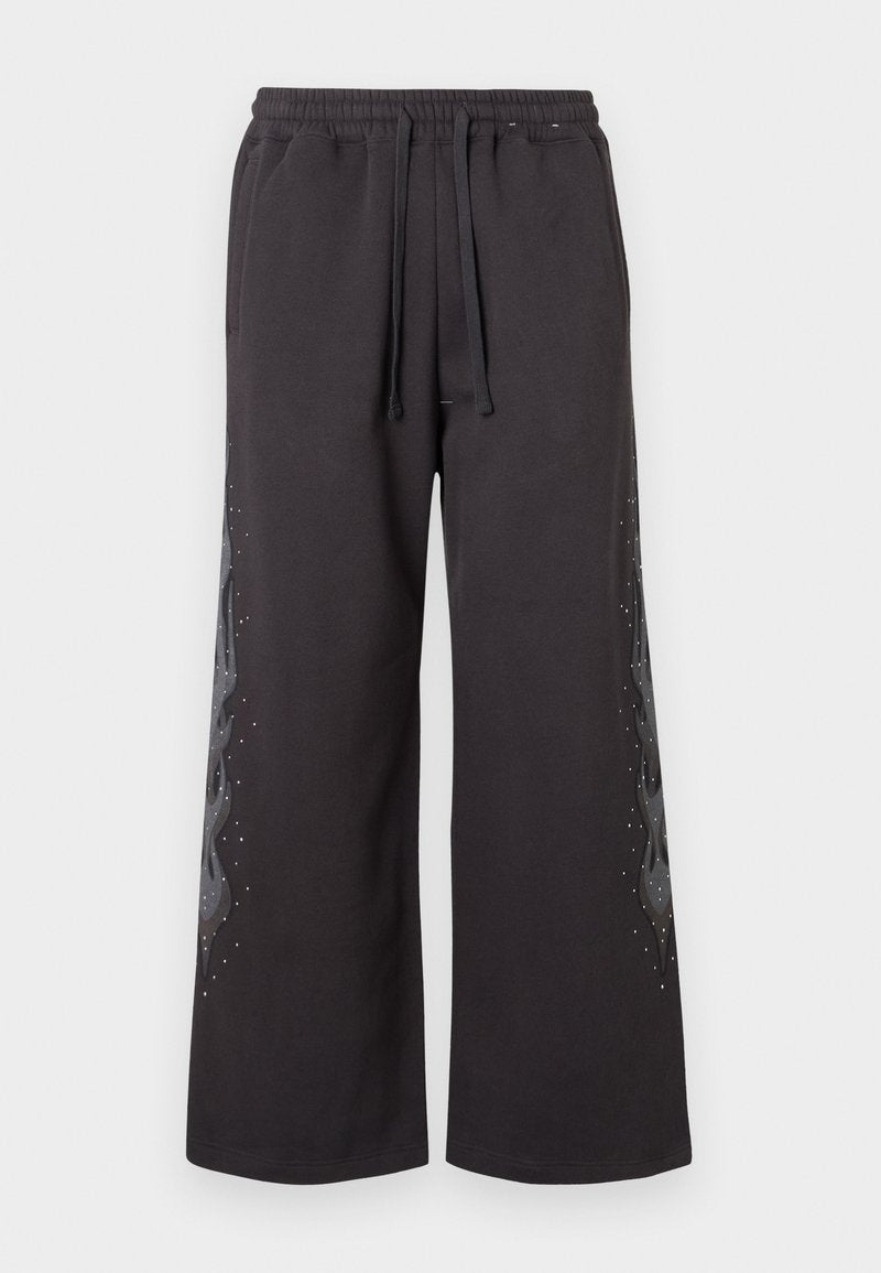 Schwarze, weit geschnittene Sweatpants mit elastischem Bund, verziert mit einem grauen Flammendesign an der Seite, akzentuiert mit kleinen Strasssteinen.