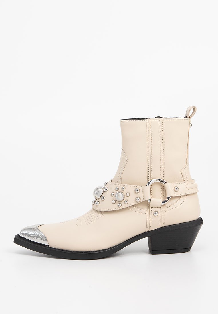 Beige Leder Stiefeletten mit silberner Zehenkappe, dekorativem Riemen mit Perlen und Nieten, seitlichem Reißverschluss und einem leichten Absatz.