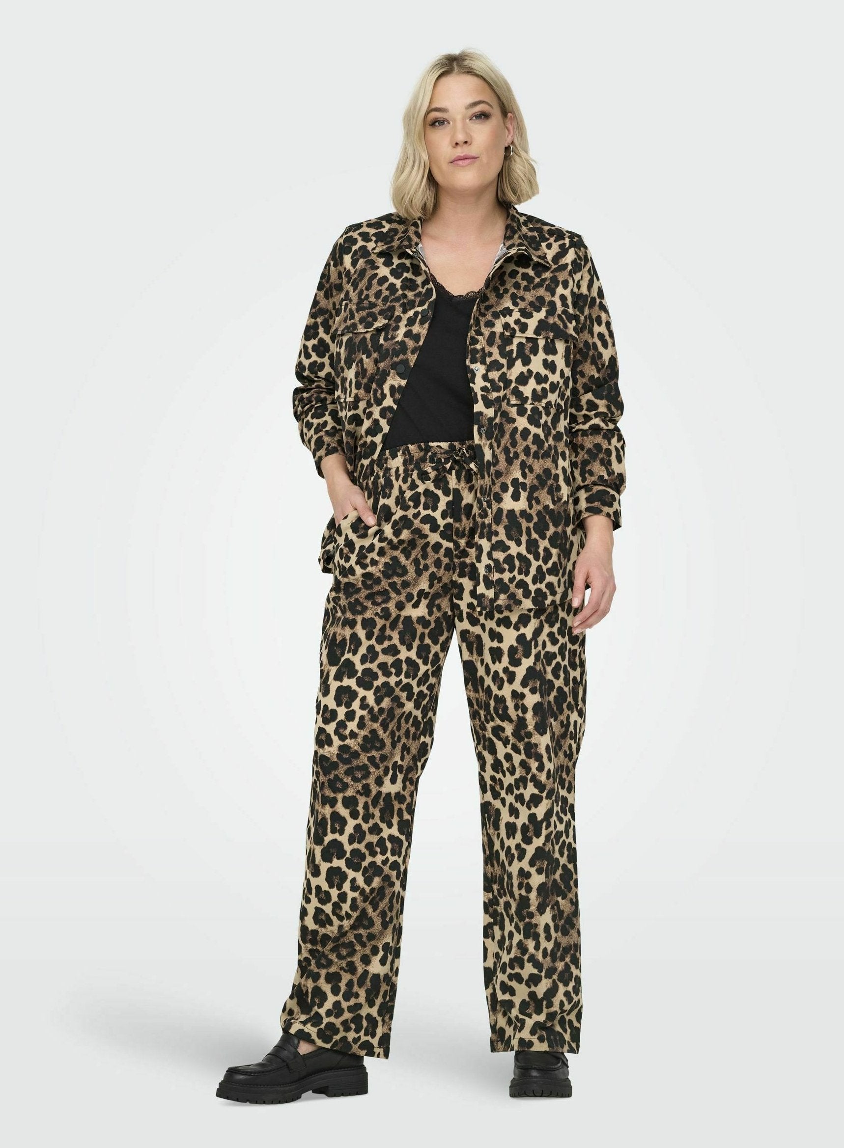 Leopardenmuster Jacke und Hose in Beige und Schwarz, mit einem lockeren Schnitt, Taschen und einem kragen Design. Kombiniert mit schwarzem Schuhwerk.