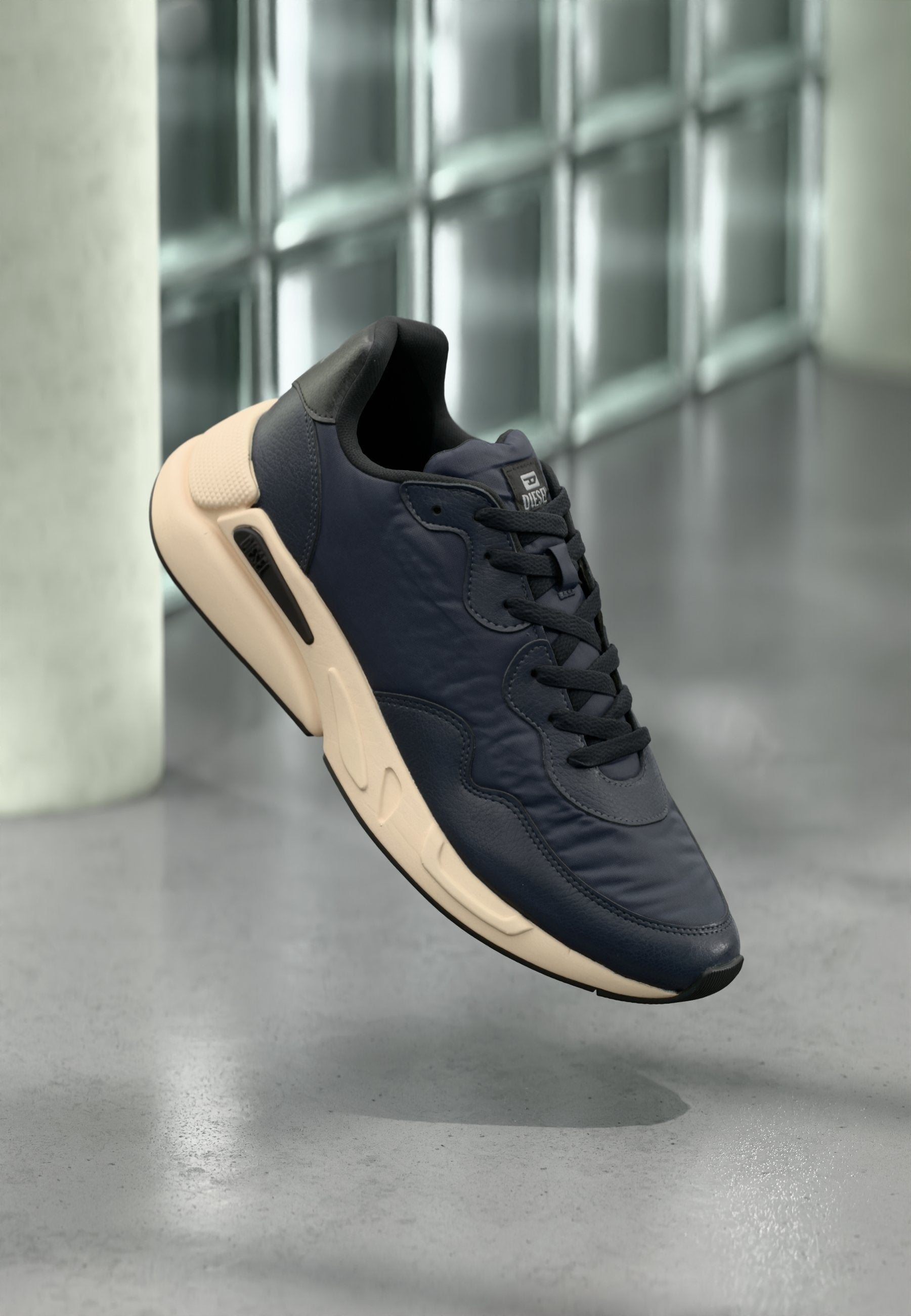 Marineblaue Sneaker mit strukturiertem Obermaterial, schwarzen Akzenten und einer beigen Sohle. Verfügt über ein Schnürdesign und sichtbare Air-Dämpfungsdetails.