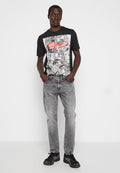 Schwarzes Grafik-T-Shirt mit einem großen weißen und roten Druck, kombiniert mit verwaschenen grauen Jeans und schwarzen Sneakern mit weißen Akzenten.