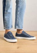 Blaue Canvas-Sneaker mit einer weißen Gummisohle, ausgestattet mit runden Schnürsenkeln und Metallösen. Das Design ist niedrig geschnitten mit einer eleganten Silhouette.