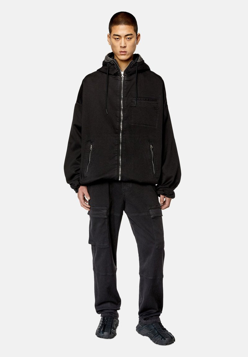 Schwarzer Hoodie mit Reißverschluss, Fronttasche und Kordelzugkapuze, kombiniert mit eng anliegenden schwarzen Cargo-Hosen mit Seitentaschen und Nähten.