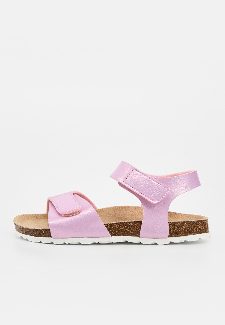 Rosa Kindersandale mit verstellbaren Riemen, Korkfußbett und weißer Gummisohle, seitlich auf weißem Hintergrund dargestellt.