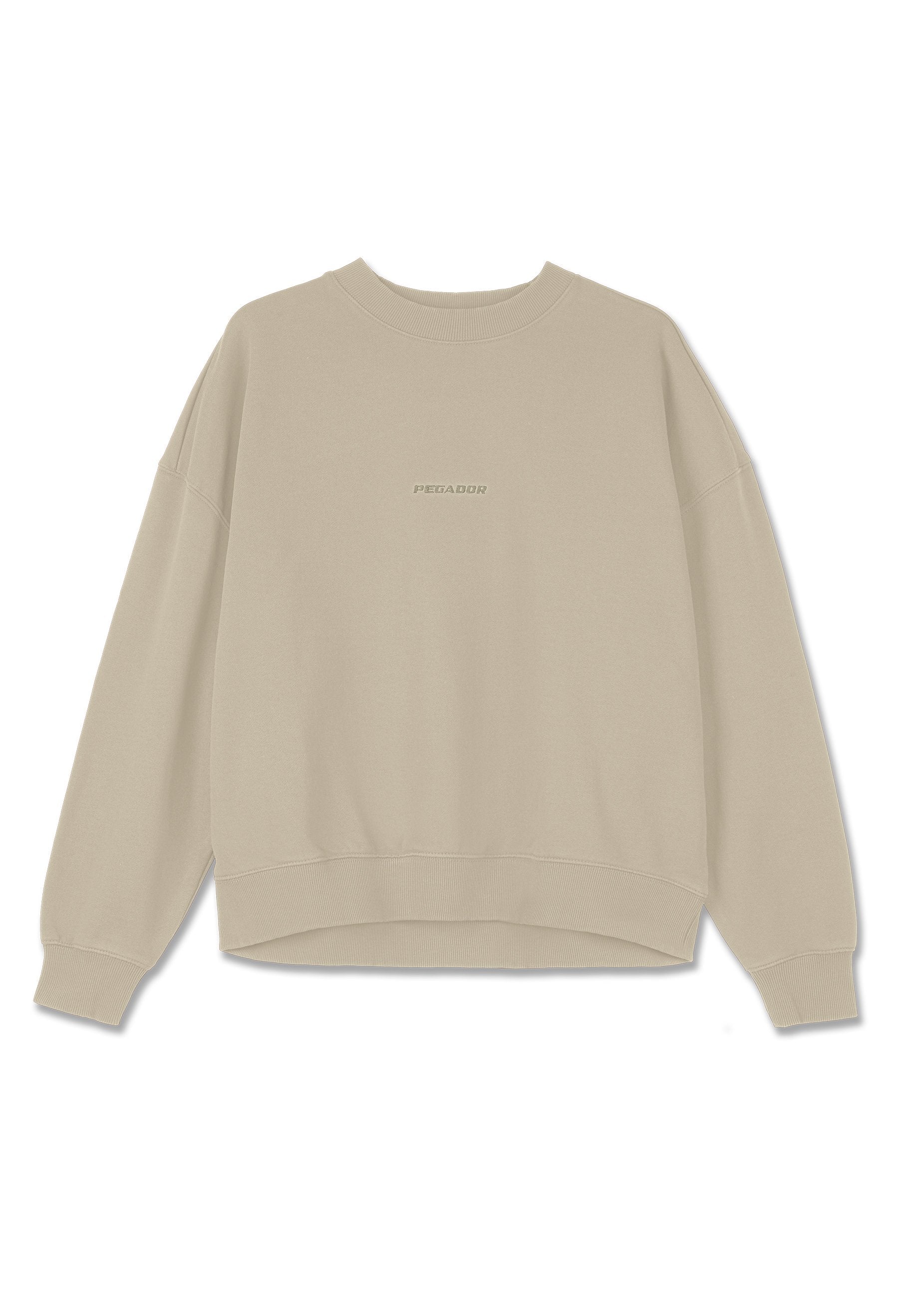 Beige Sweatshirt aus weichem Baumwollmaterial, mit Rundhalsausschnitt, überschnittenen Schultern und gerippten Bündchen, auf der Vorderseite mit dem Wort "PEGAADOR" bestickt.