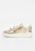 Goldfarbener metallischer Sneaker mit niedrigem Schaft, weißen Schnürsenkeln und dicker weißer Sohle, mit „PINKO“-Markentext und floralem Detail an der Ferse.