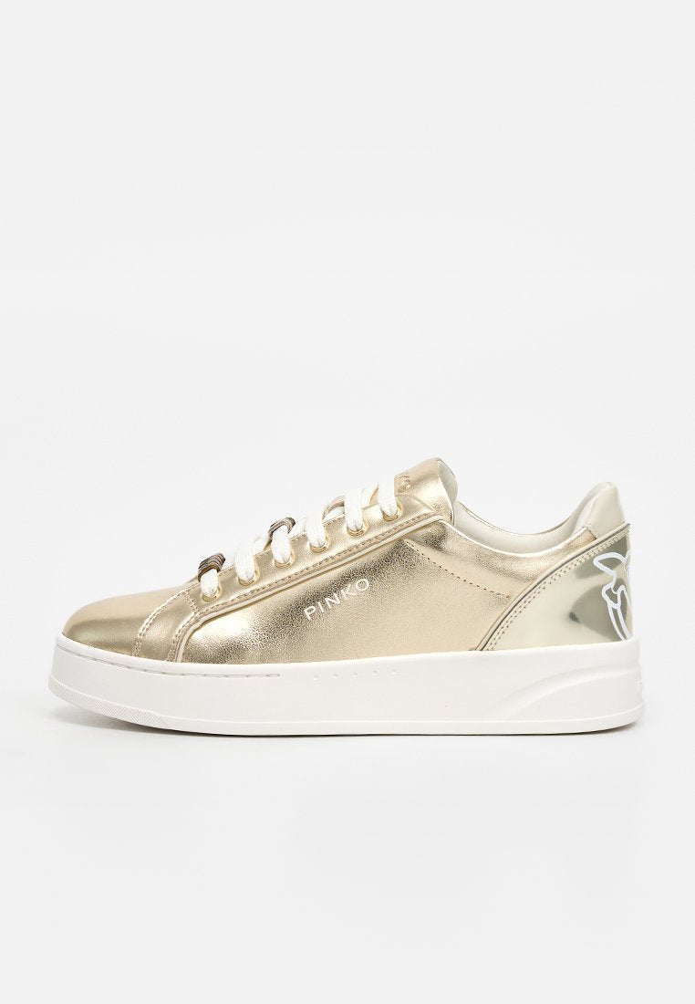 Goldfarbener metallischer Sneaker mit niedrigem Schaft, weißen Schnürsenkeln und dicker weißer Sohle, mit „PINKO“-Markentext und floralem Detail an der Ferse.