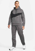 Mann trägt grauen Nike-Hoodie und passende Jogginghose mit großem schwarzem Swoosh, steht mit weißen Nike-Turnschuhen vor weißem Hintergrund.