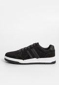 Schwarze Wildleder-Sneaker mit grauen Akzenten, weißer Gummisohle, runder Zehenpartie und kontrastierenden Schnürsenkeln. Zwei horizontale Streifen an der Außenseite.