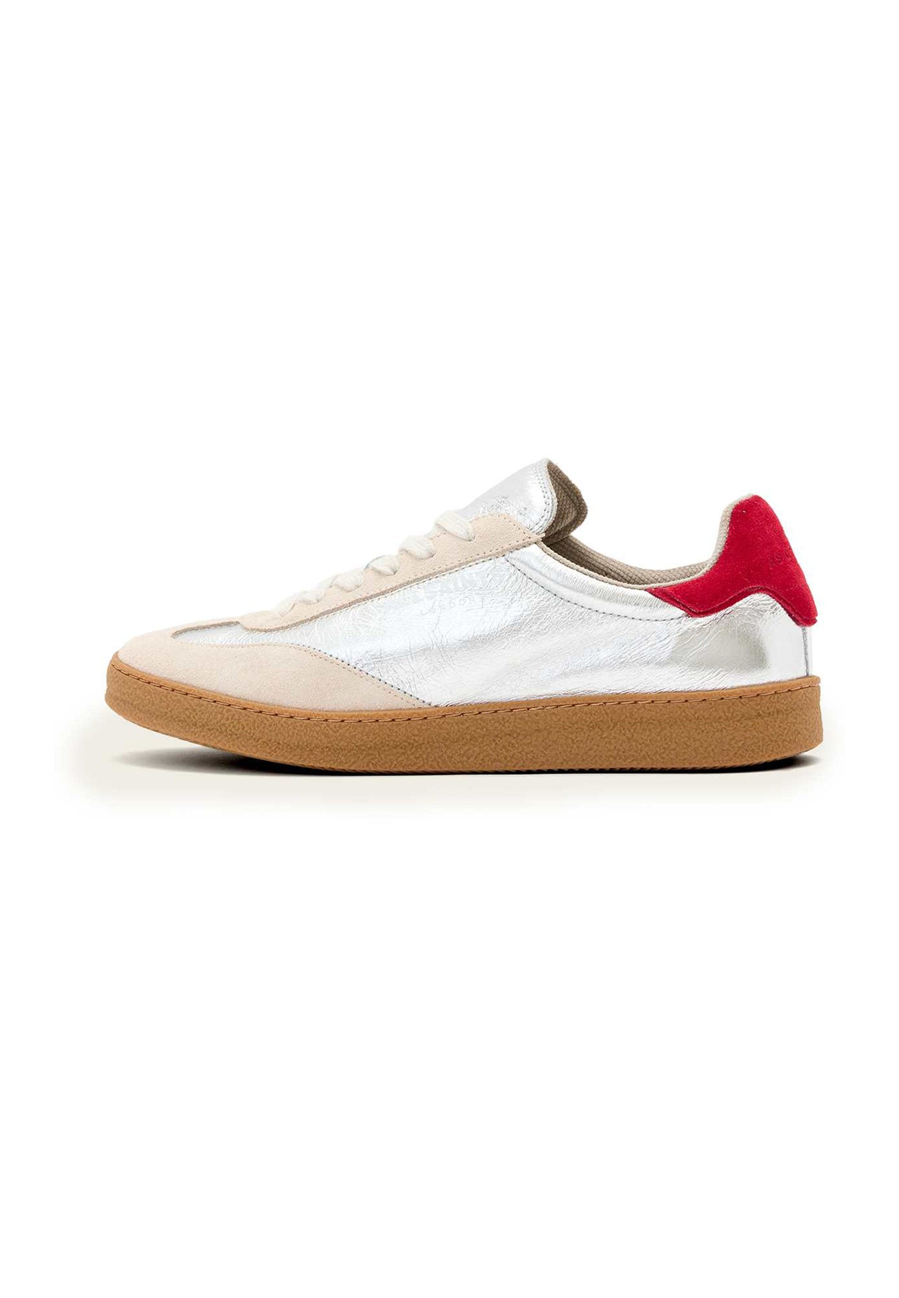Sneaker mit brauner Gummisohle, beigem Wildleder-Obermaterial, silbernen metallischen Akzenten und rotem Absatzpatch; ausgestattet mit flachen Schnürsenkeln und gesteppten Details.
