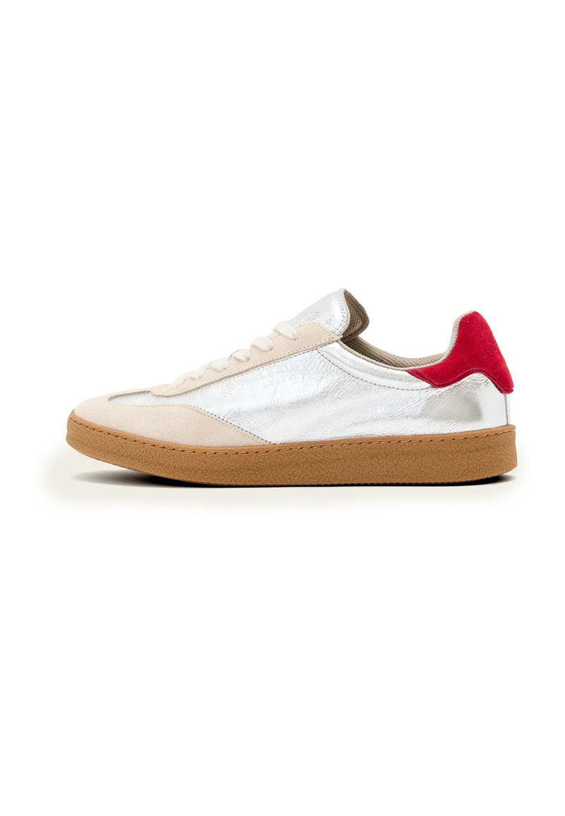 Sneaker mit brauner Gummisohle, beigem Wildleder-Obermaterial, silbernen metallischen Akzenten und rotem Absatzpatch; ausgestattet mit flachen Schnürsenkeln und gesteppten Details.
