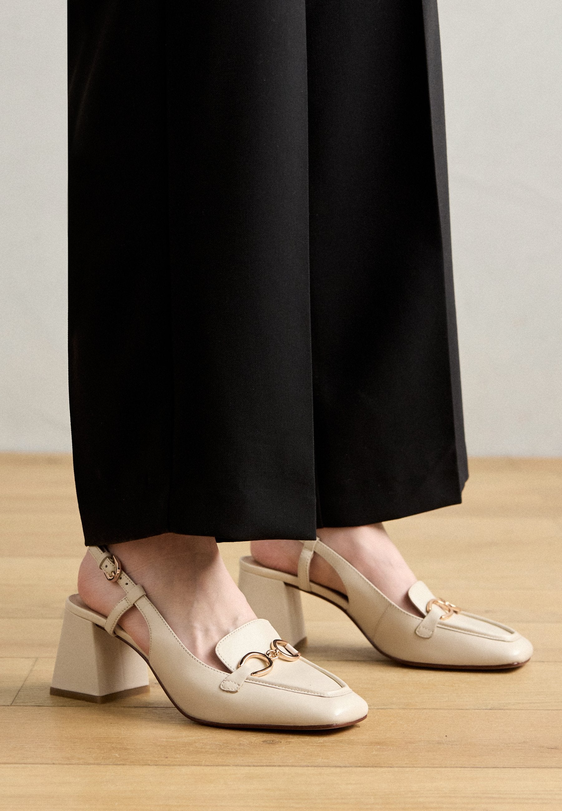 Beige Leder Slingback-Pumps mit quadratischer Zehenpartie und robustem Absatz. Mit einem goldfarbenen Doppelkreis-Akzent auf dem Vorderfuß.