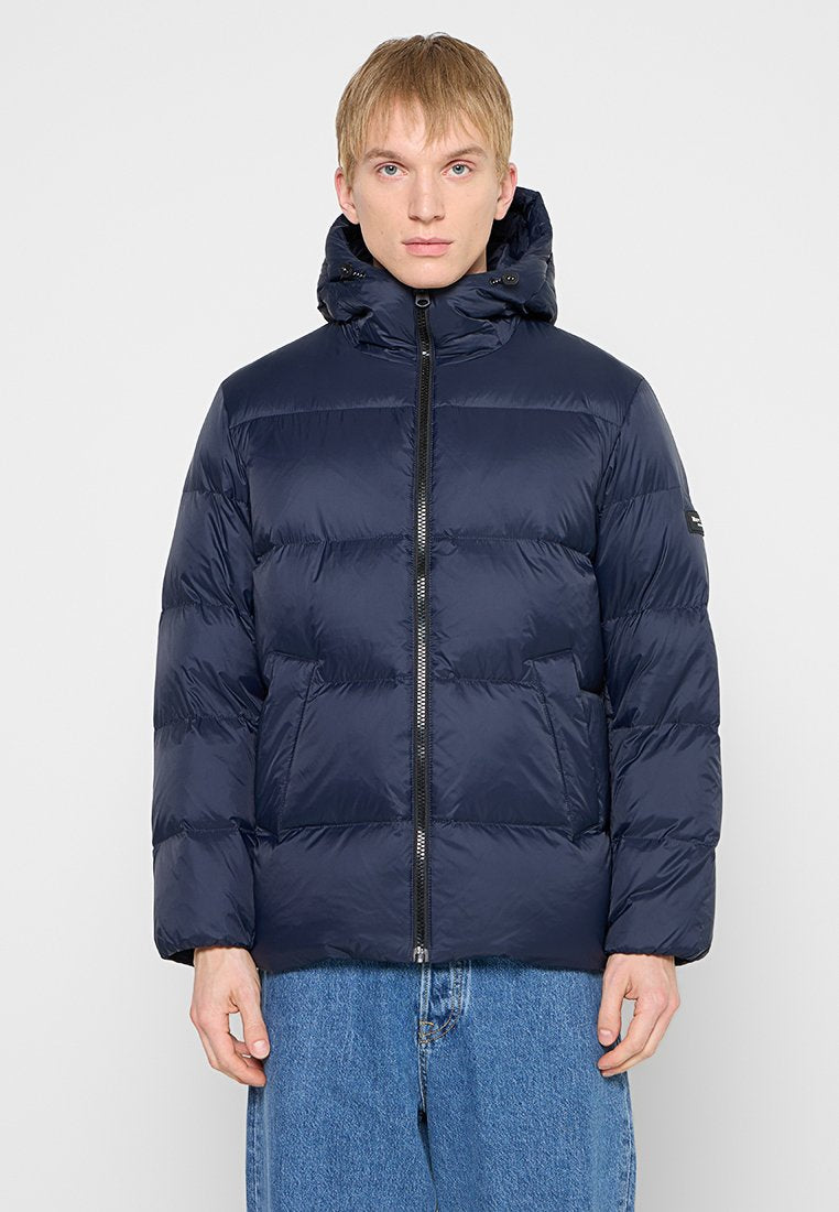 Marineblaue Steppjacke mit Reißverschluss, gepolstertem Design und Kapuze. Verfügt über seitliche Taschen und ein kleines Logo am Ärmel.