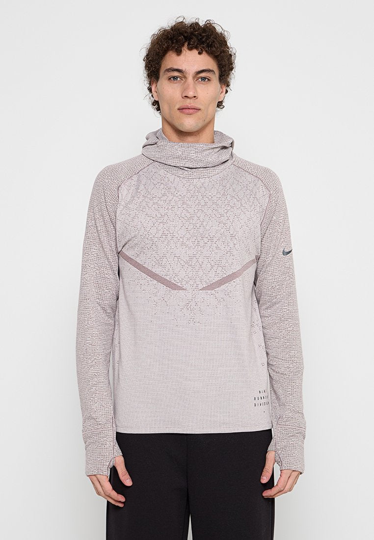 Langärmliges, hellgraues Trainingsshirt mit hohem Kragen, strukturierter Stoff und dezenten dunklen Akzenten. Mit diagonalen Steppnähten.