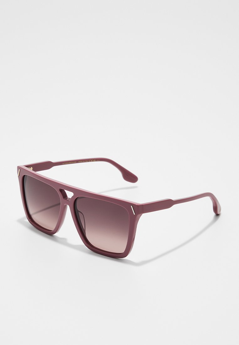 Quadratische bordeauxfarbene Sonnenbrille mit verlaufenden dunklen Gläsern und einem kleinen Ausschnitt in der Nähe der Brücke, die auf einer weißen Oberfläche liegt.