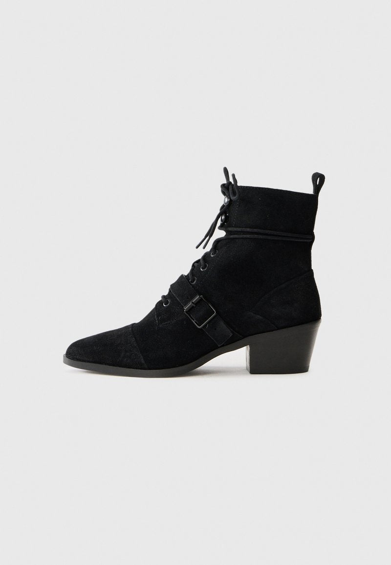 Schwarze Wildleder Stiefelette mit spitzer Zehenform, Schnürung an der Vorderseite, verstellbarem Riemen mit Schnalle und gestapeltem Absatz. Glatte Textur mit matter Oberfläche.