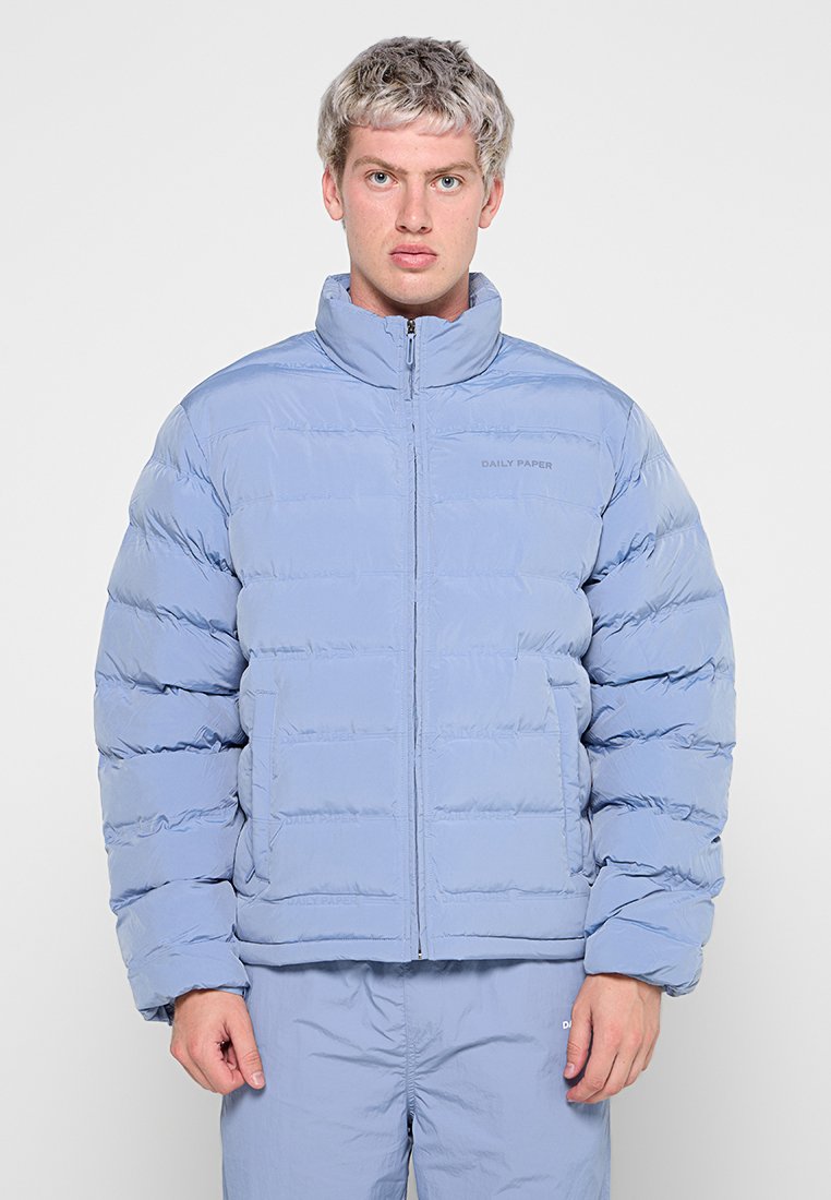 Helle blaue Puffjacke mit hohem Kragen, Reißverschluss und horizontalen Nähten. Verfügt über ein Logo auf der linken Seite und seitliche Taschen.