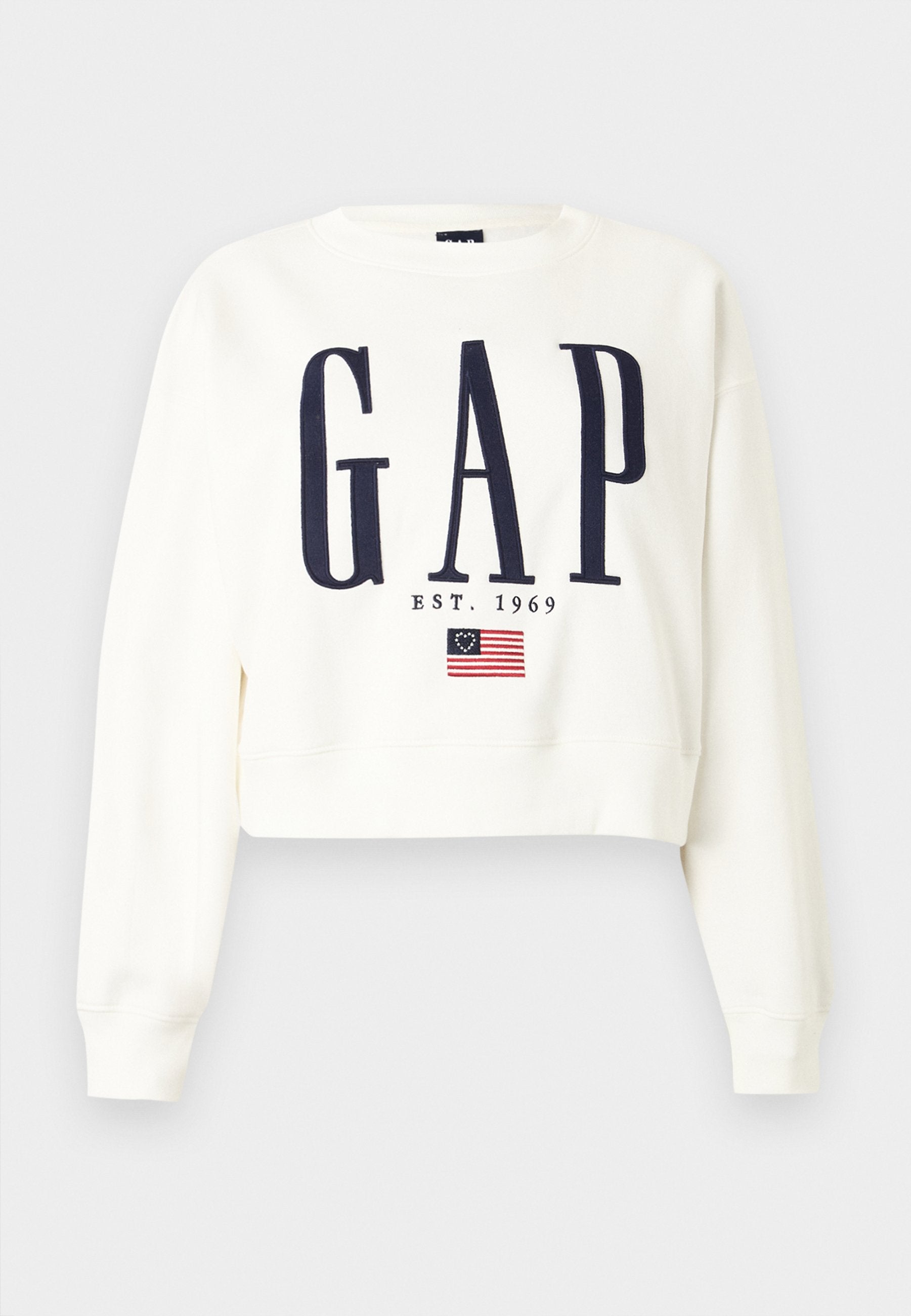 Weißer, kurzer Pullover mit großem, dunkelblauem "GAP"-Schriftzug, darunter "EST. 1969" und einer kleinen Grafik der Betsy Ross amerikanischen Flagge.