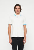 Junger Mann, der ein weißes Poloshirt mit blauem Besatz und schwarze Hose trägt, vor einem einfachen weißen Hintergrund stehender.