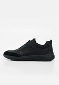 Schwarzer Low-Top-Sneaker mit strukturierter Sohle, gemischten Leder- und Stoffpaneelen sowie Zuglaschen an Zunge und Ferse vor weißem Hintergrund.