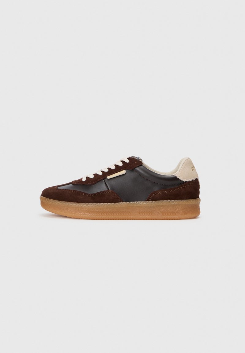 Braune Wildleder- und Leder-Sneaker mit einer Gummisohle, die cremefarbene Akzente und weiße Schnürsenkel aufweist. Runde Zehenform und minimale Details.