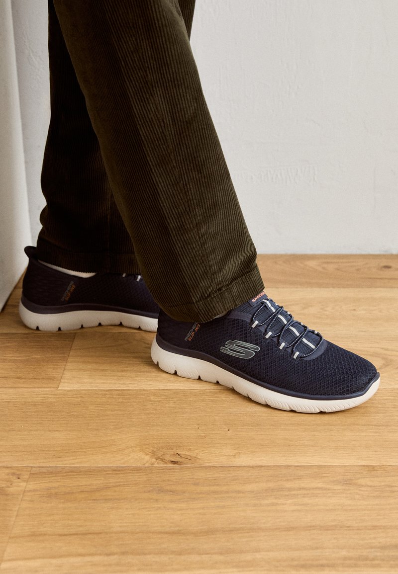 Marinefarbene Netzsneaker mit weißen Sohlen, ausgestattet mit elastischen Schnürsenkeln und einem Logodetail. Lässiges Design mit leichter Konstruktion.