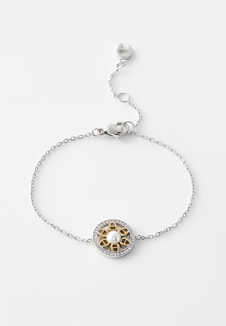 Silberne Kettenarmband mit einem runden Anhänger mit goldenen Akzenten, einer zentralen Perle und einem Rand aus klaren Strasssteinen.