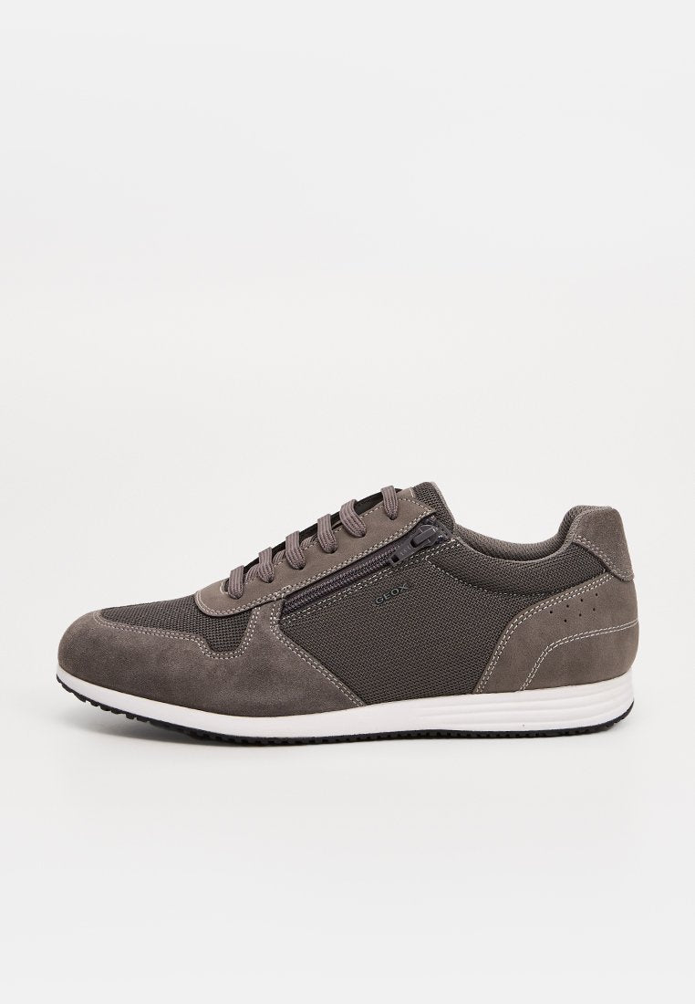 Grauer Freizeitsneaker mit Veloursleder- und Mesh-Elementen, Schnürung vorne, Seitlicher Reißverschluss, weiße Sohle und schwarze Laufsohle, von der Außenseite betrachtet.