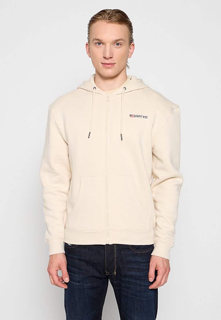 Beige Kapuzenpullover mit Reißverschluss, Kordelzügen, Vordertaschen und einem kleinen Logo oben links. Hergestellt aus weichem Stoff mit glatter Textur.