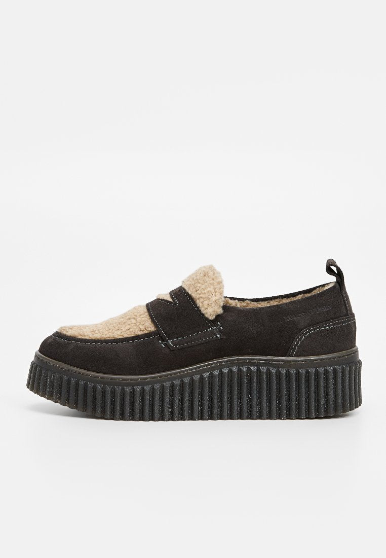 Schwarzer Wildleder-Slipper mit einer beigefarbenen Fellfront, strukturiertem Plattformsohle und kontrastierenden Steppdetails.