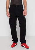 Schwarze Cargo-Hosen mit mehreren Taschen, aus strapazierfähigem Stoff, mit geradem Bein und Knopfverschluss am Bund. Rote Schuhe ergänzen den Look.