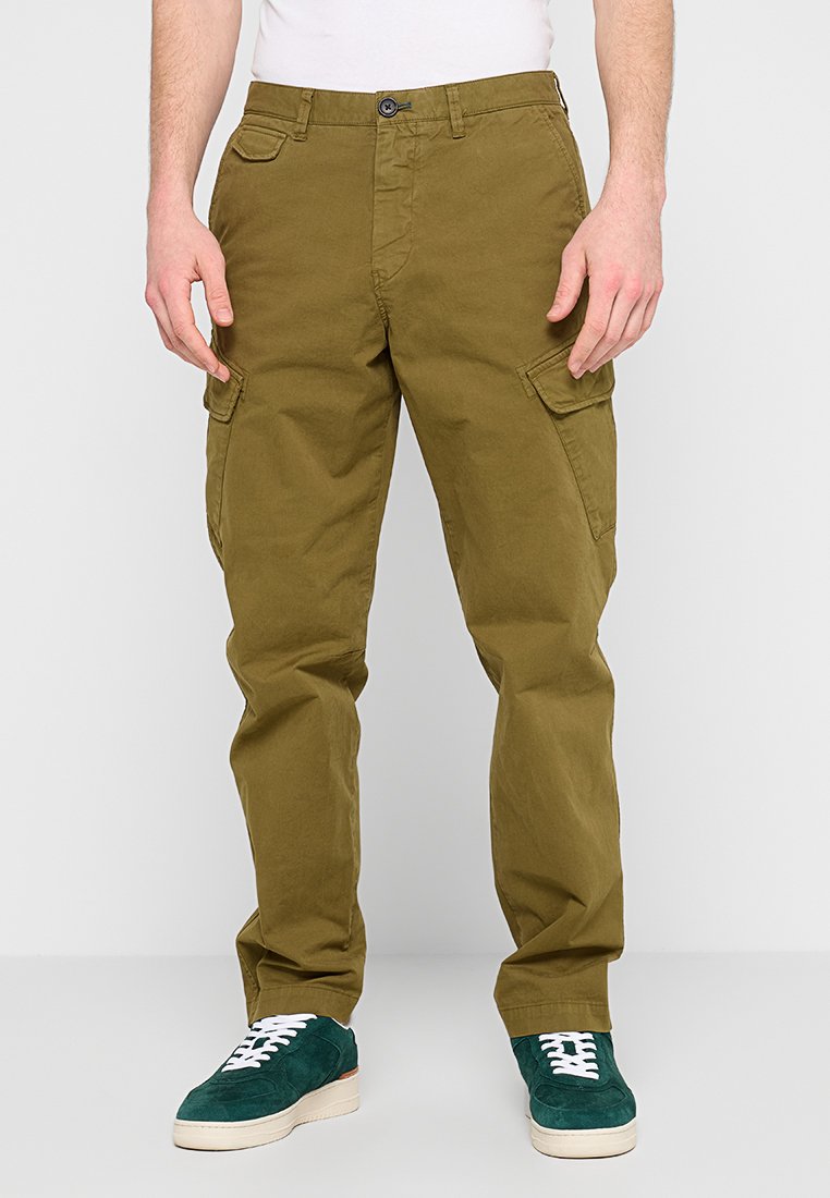 Khakifarbene Cargo-Hosen mit entspannter Passform, ausgestattet mit Seitentaschen, einem Knopfverschluss und einer glatten Baumwolltextur. Kombiniert mit grünen Wildledersneakern.