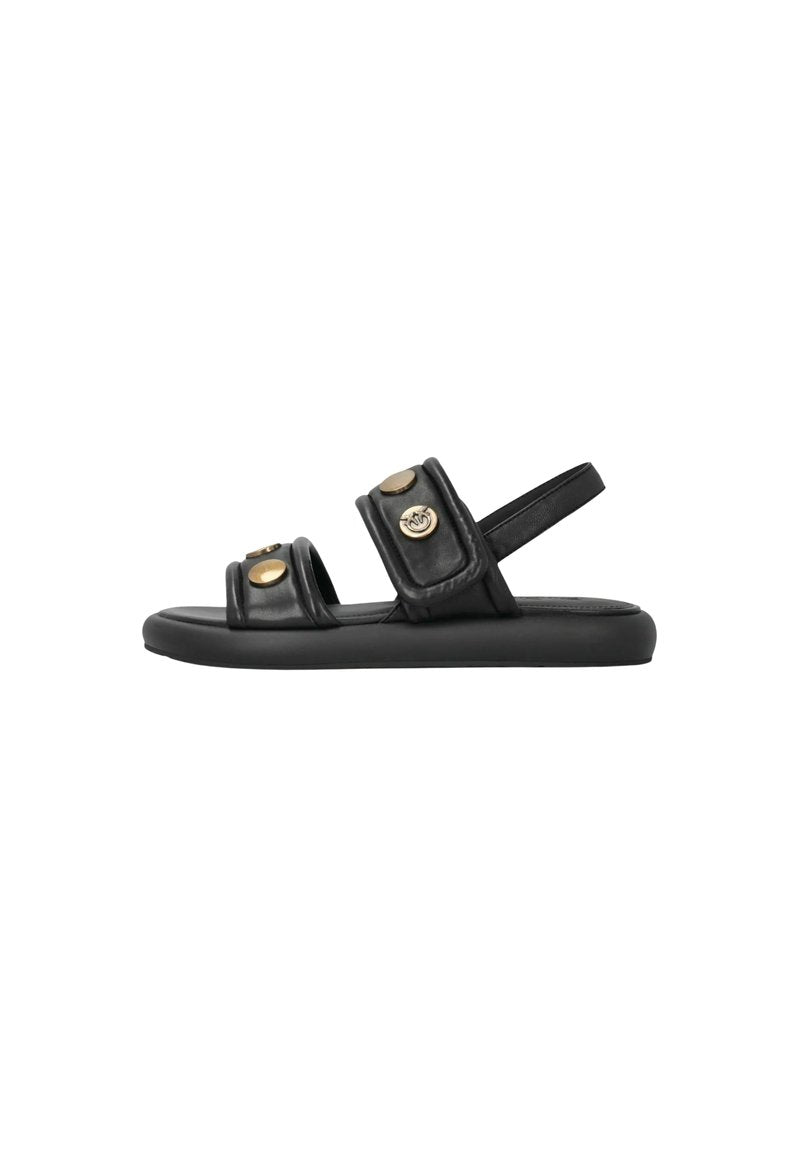 Schwarze flache Sandale mit zwei gepolsterten Riemen, goldfarbenen Knopfdetails und Fersenriemen auf weißem Hintergrund.