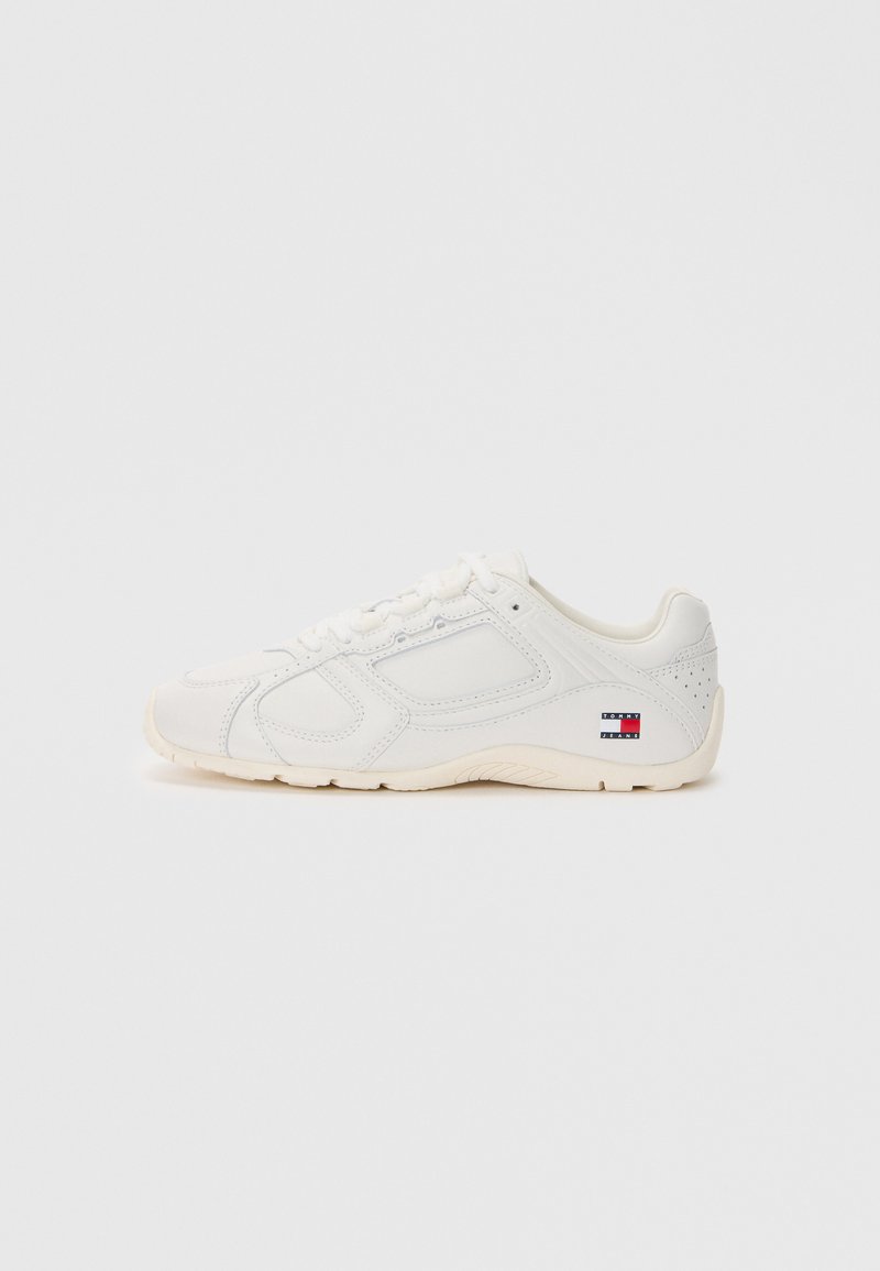 Weißer Sportschuh mit glattem Lederoberteil, strukturierten Akzenten, runder Zehenpartie und gerundeter Gummisohle. Mit Logo-Patch an der Ferse.