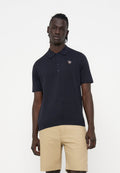 Mann trägt ein schwarzes kurzärmliges Polo mit kleinem Zebra-Logo und beigefarbenen knielangen Shorts, steht vor einem weißen Hintergrund.