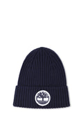 Marineblaue Strickmütze mit gerippter Textur und umgeschlagenem Saum, vorne mit einem runden weißen Patch mit einem Baum-Logo.