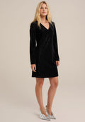 Schwarzes Samtkleid mit langen Ärmeln, V-Ausschnitt und taillierter Passform, das einen subtilen Schimmer hat und knielang ist. Silbern Wedges.