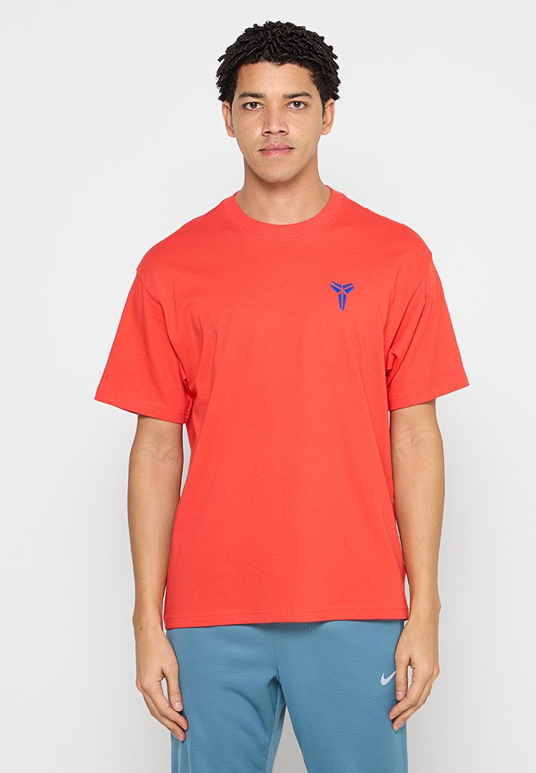 Rotes Baumwoll-T-Shirt mit kurzen Ärmeln, lockerer Passform und einem blauen Logo auf der linken Brust. Glatte Textur, Rundhalsausschnitt.