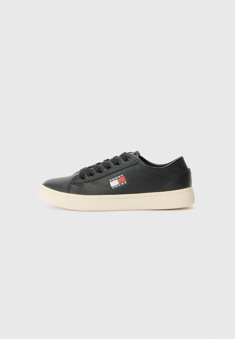 Schwarze Ledersneaker mit einer weißen Gummisohle und einem seitlichen Logopatch mit roten und blauen Akzenten. Klassisches Schnürdesign mit abgerundetem Zehenbereich.
