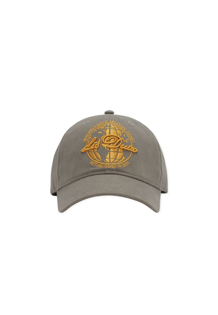 Graue Baseballkappe mit gebogenem Schirm, versehen mit golden besticktem Text und Globus-Design auf der Vorderseite. Baumwollmaterial mit glatter Textur.