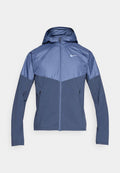 Marineblaue Nike-Jacke mit Kapuze, mit einem kontrastierenden helleren blauen oberen Abschnitt, Reißverschluss und zwei Seitentaschen. Glattes Material.