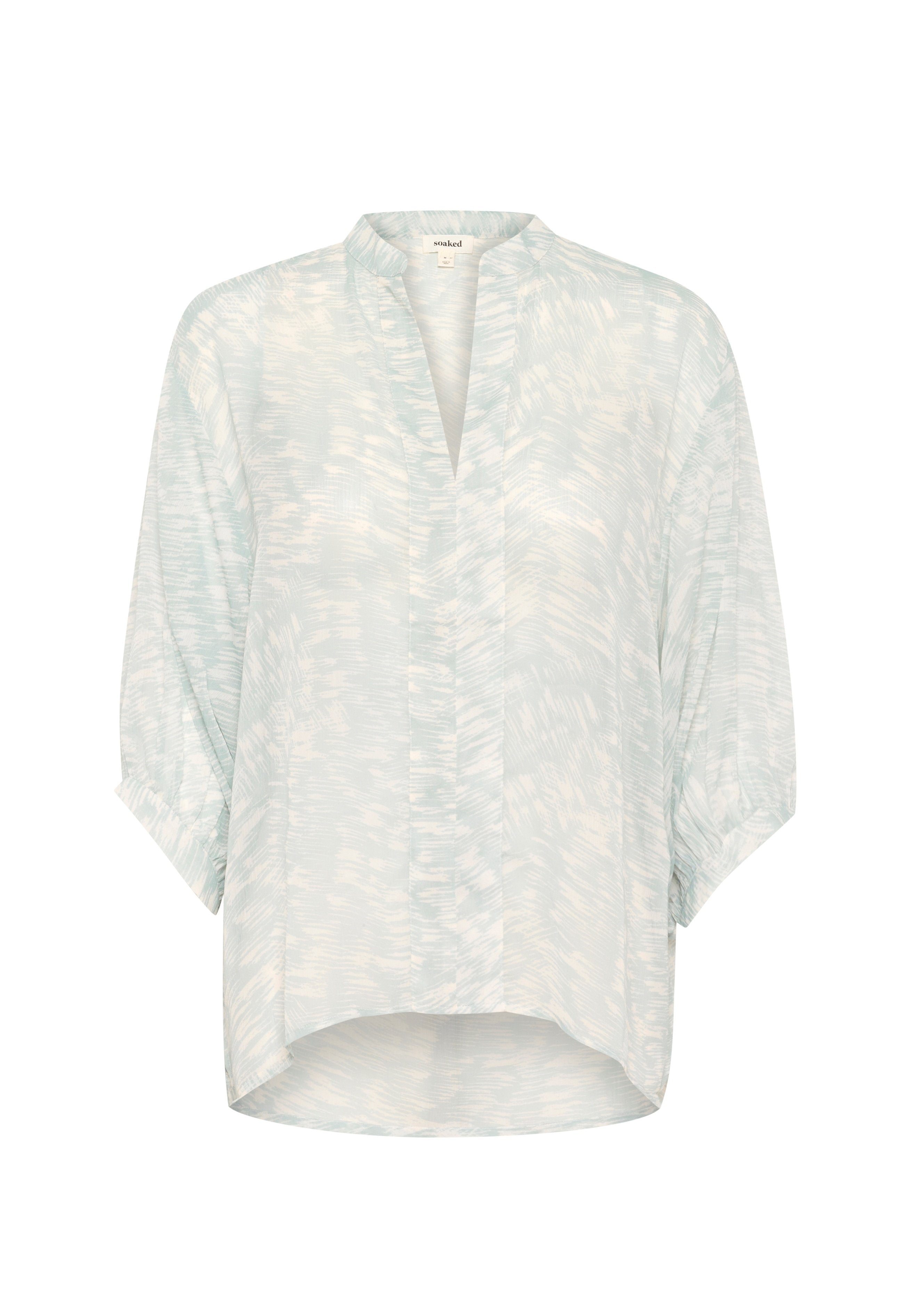 Helleblaue Bluse aus einem weichen, strukturierten Stoff. Sie hat einen V-Ausschnitt, kurze Ärmel und ein dezentes abstraktes Muster.
