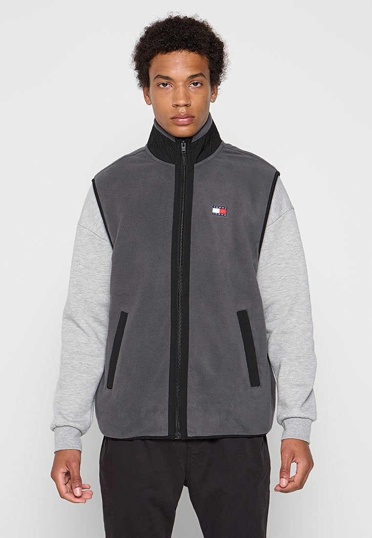 Grauer Fleece-Weste mit grauen Ärmeln, hohem Kragen und Frontreißverschluss. Verfügt über schwarze Akzente und ein kleines Logopatch auf der linken Brust.