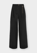 Schwarze High-Waist-Weitbein-Hose mit Falten, passendem Gürtel mit goldener Schnalle und goldenem Kettenaccessoire auf der rechten Seite.