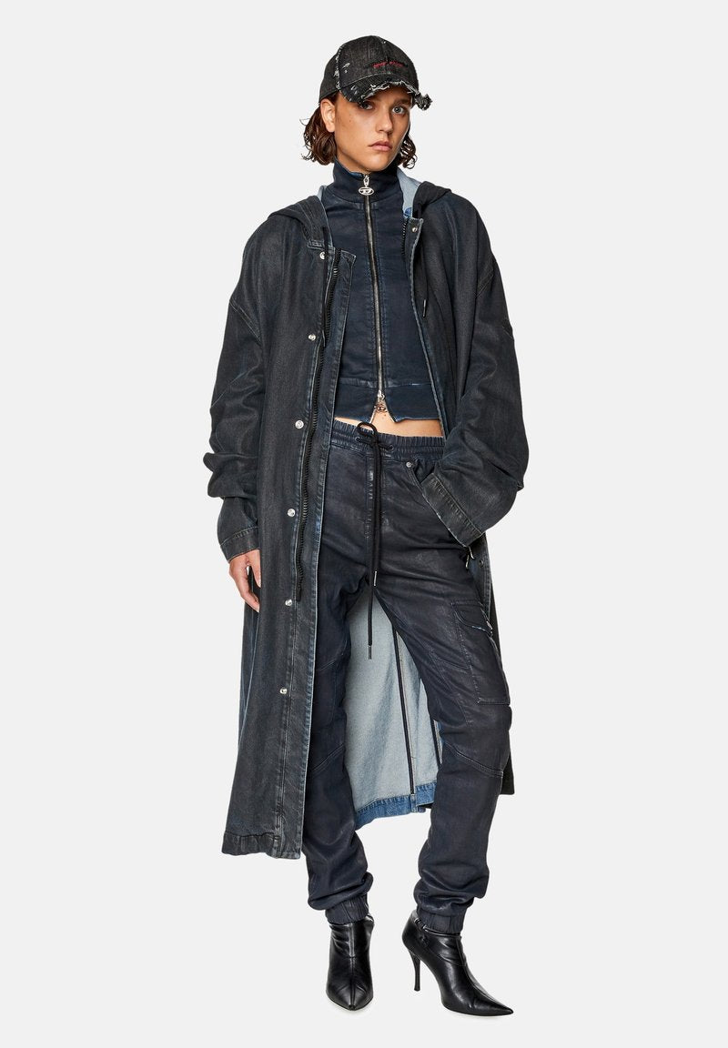 Dunkelblauer Jeansmantel, kurzer navyfarbener Reißverschlussoberteil, passende Jogginghose und spitze schwarze Absätze. Baseballkappe mit ausgefransten Rändern und Logodetail.