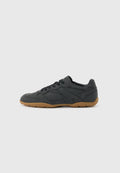Schwarzer Sneaker mit niedrigem Profil, beigefarbener Gummisohle, seitlichen Schnürsenkeln und dezentem geprägtem Markennamen an der Seite, vor einfarbigem Hintergrund.