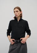 Schwarzer Langarm-Half-Zip-Pullover mit einem dezenten Logo, kombiniert mit grauen, taillierten Hose und einem gewebten schwarzen Gürtel. Glatte Textur, figurnahes Design.