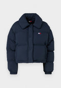 Marineblaue Steppjacke mit einem cropped Design, ausgestattet mit einem großen Kragen, Frontknöpfen und einem kleinen Logo mit roten und weißen Akzenten auf der Brust.
