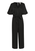 Schwarzer Jumpsuit aus glattem Stoff, mit V-Ausschnitt, kurzen Glockenärmel, Bindegürtel in der Taillenhöhe und knöchellangen weiten Beinen. Mit Reißverschluss auf der Rückseite.
