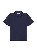 Marineblaues Polohemd mit kurzen Ärmeln und einem halben Reißverschluss am Kragen, strukturierter Stoff und subtil gemustertes geometrisches Design. Auf dem Kragen befindet sich ein Etikett mit der Aufschrift "LES DEUX."